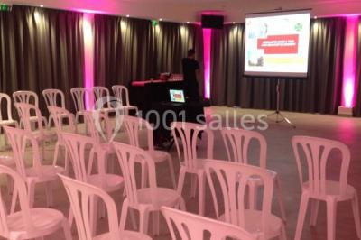 Kiosque en toit de chaume entouré d'arbres, situé dans une cour pavée avec des voiles d'ombrage.