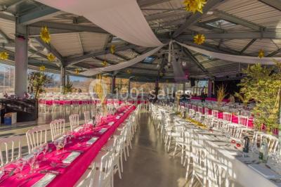 Kiosque en toit de chaume entouré d'arbres, situé dans une cour pavée avec des voiles d'ombrage.