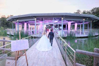 Kiosque en toit de chaume entouré d'arbres, situé dans une cour pavée avec des voiles d'ombrage.