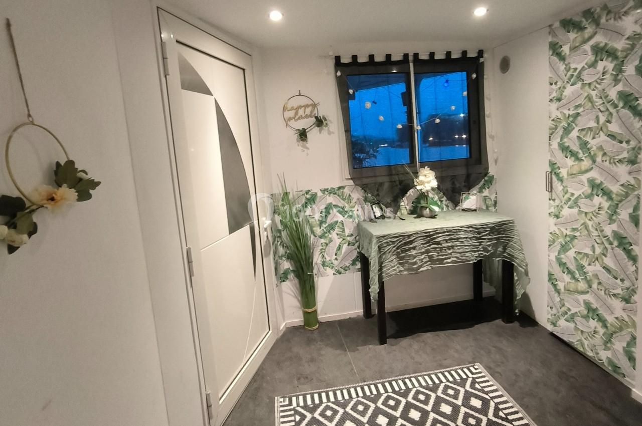 Pièce lumineuse décorée de motifs végétaux, avec une table recouverte d'un tissu vert et une fenêtre ornée de guirlandes.