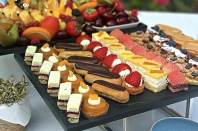 Plateau de mini-sandwichs variés, verrines et décorations florales comestibles, présenté sur une table.