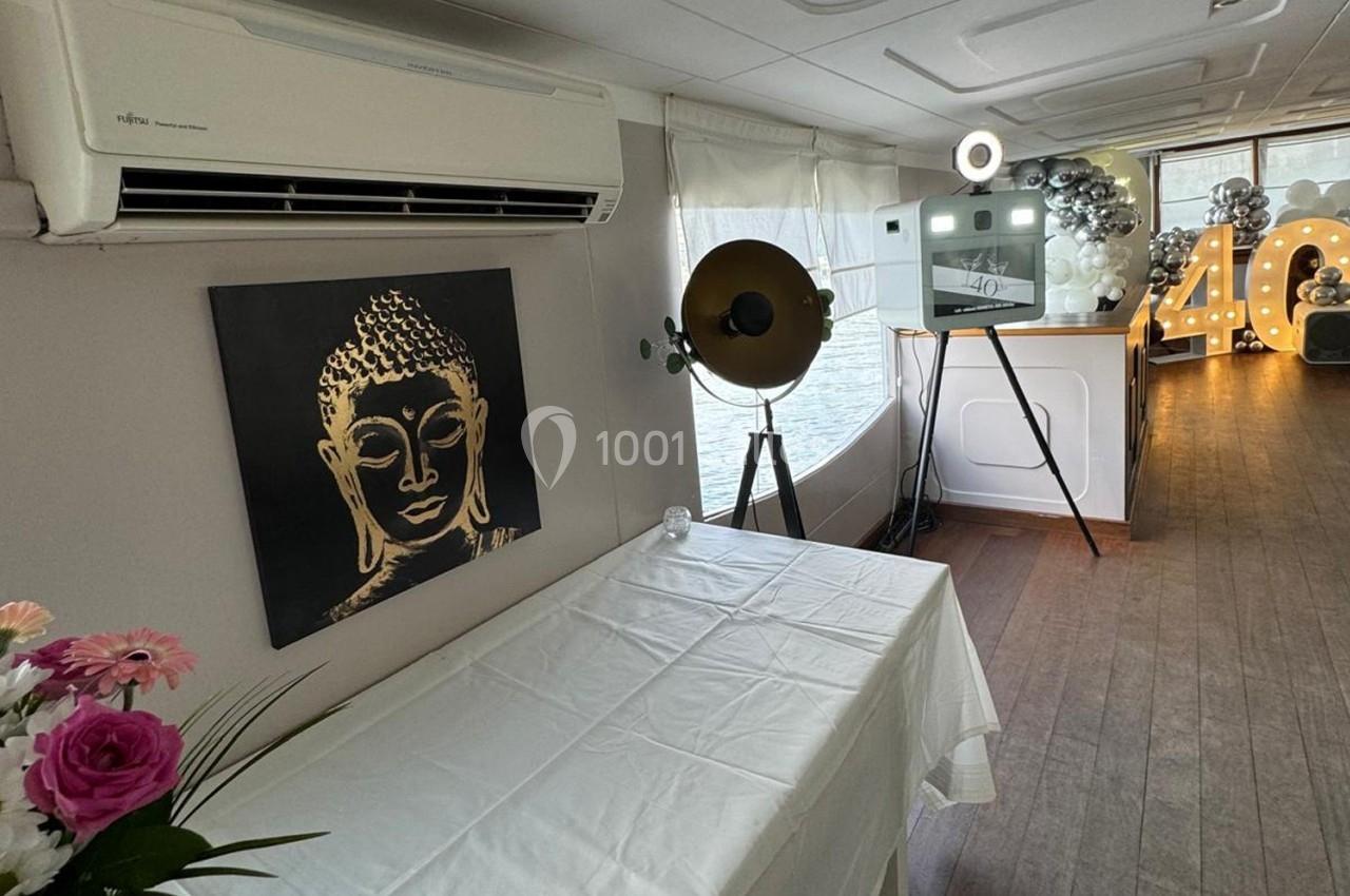 Salle décorée avec une table blanche, un tableau représentant Bouddha, des ballons et un chiffre lumineux ’40’.