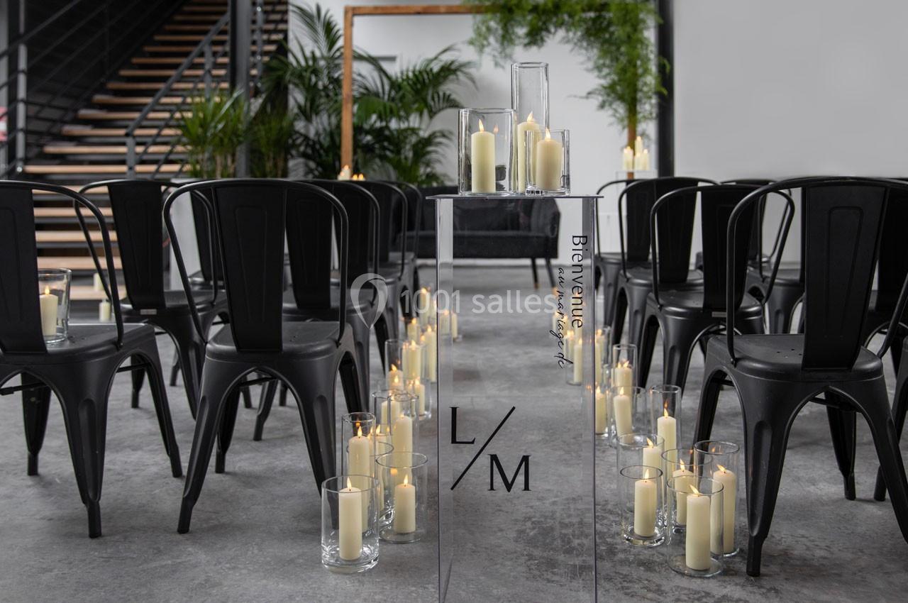 Chaises noires alignées face à un autel minimaliste avec des bougies dans des vases en verre, dans un espace moderne.