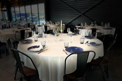 Espace extérieur avec sol en gravier, arbres, tente beige tendue et clôture en bois sous un ciel nuageux.