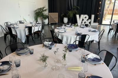 Espace extérieur avec sol en gravier, arbres, tente beige tendue et clôture en bois sous un ciel nuageux.