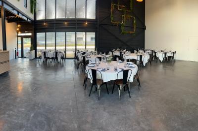 Espace extérieur avec sol en gravier, arbres, tente beige tendue et clôture en bois sous un ciel nuageux.