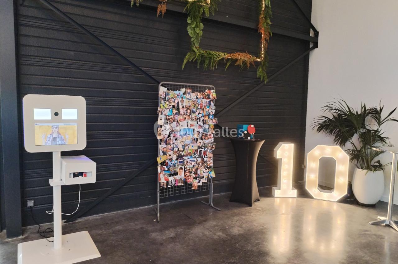 Borne photo, panneau de photos, décoration lumineuse ’10’ et plantes dans un espace intérieur moderne.
