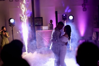 Espace extérieur avec sol en gravier, arbres, tente beige tendue et clôture en bois sous un ciel nuageux.