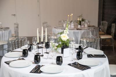 Espace extérieur avec sol en gravier, arbres, tente beige tendue et clôture en bois sous un ciel nuageux.