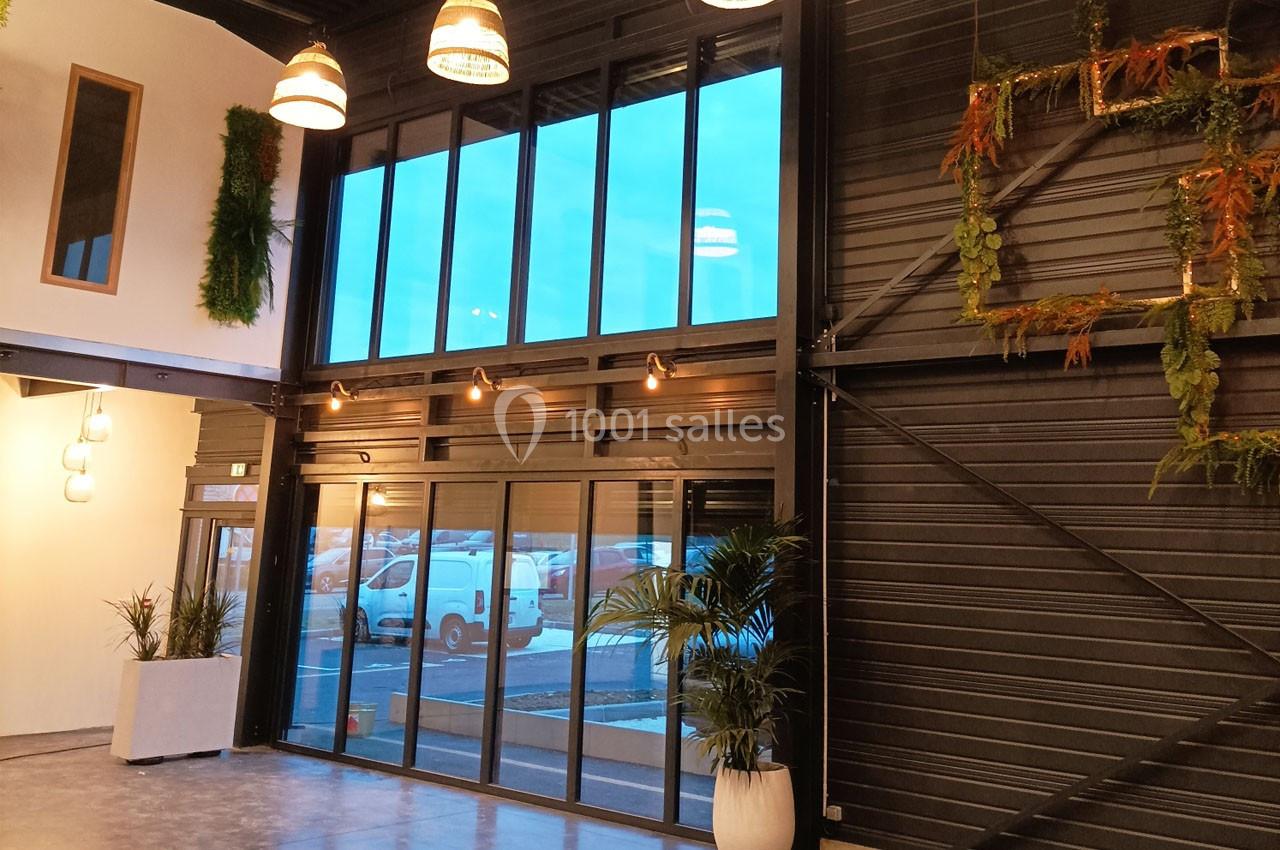 Grande baie vitrée dans un espace intérieur moderne avec des plantes suspendues et des murs en métal sombre.