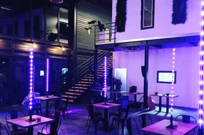 Espace extérieur avec sol en gravier, arbres, tente beige tendue et clôture en bois sous un ciel nuageux.