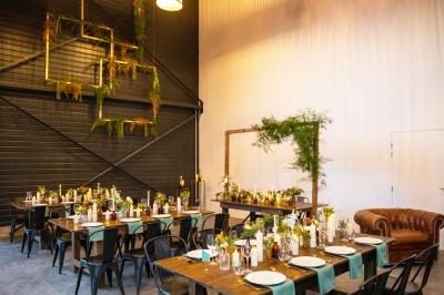 Espace extérieur avec sol en gravier, arbres, tente beige tendue et clôture en bois sous un ciel nuageux.