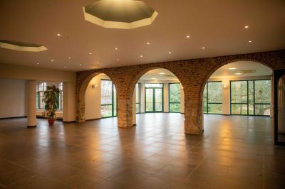Salle vide avec de grandes baies vitrées donnant sur un espace extérieur verdoyant.