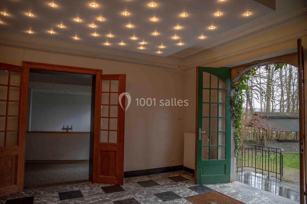 Intérieur avec sol en marbre, portes vitrées ouvertes et vue sur un jardin par une porte verte.