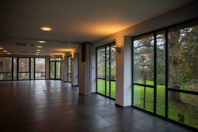 Salle vide avec de grandes baies vitrées donnant sur un espace extérieur verdoyant.