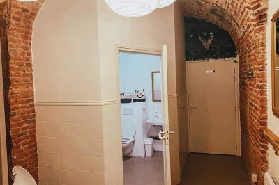 Lavabo blanc avec miroir dans une pièce aux murs en pierre et éclairée par des lampes suspendues rondes.