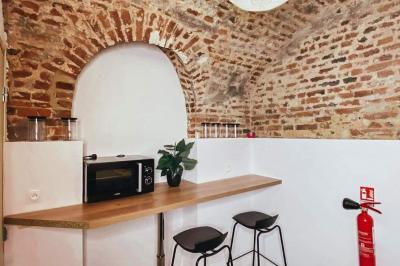 Lavabo blanc avec miroir dans une pièce aux murs en pierre et éclairée par des lampes suspendues rondes.