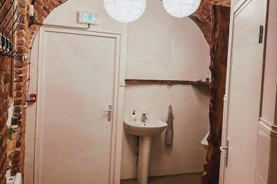 Lavabo blanc avec miroir dans une pièce aux murs en pierre et éclairée par des lampes suspendues rondes.