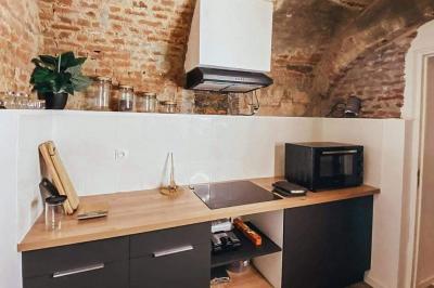 Lavabo blanc avec miroir dans une pièce aux murs en pierre et éclairée par des lampes suspendues rondes.