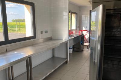 Salle de réception décorée avec des tables dressées, nappes blanches, serviettes rouges et centre de table fleuri.