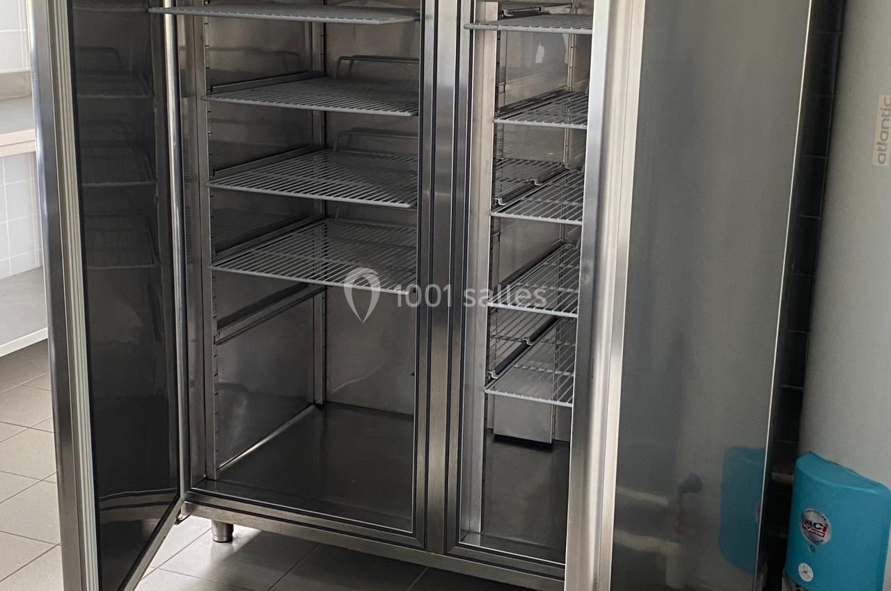 Armoire réfrigérée en acier inoxydable à double porte ouverte, montrant des étagères vides à l'intérieur.