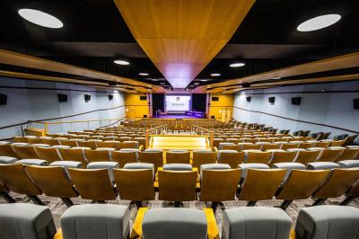 Entrée lumineuse avec tapis foncé, murs blancs, escalier en bois et plantes visibles à travers une cloison vitrée.