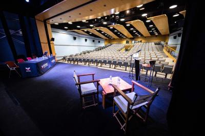 Entrée lumineuse avec tapis foncé, murs blancs, escalier en bois et plantes visibles à travers une cloison vitrée.