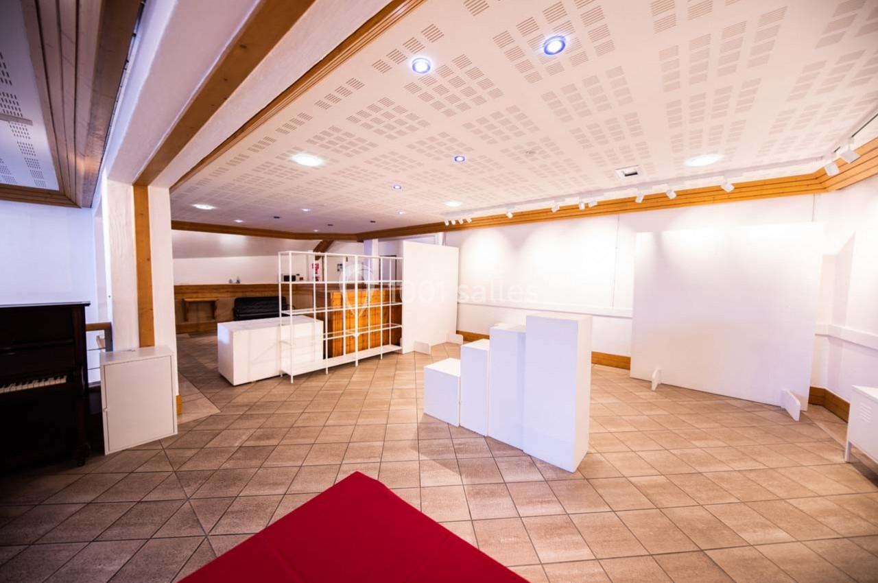 Salle lumineuse avec carrelage au sol, murs blancs, mobilier minimaliste et plafond avec éclairage intégré.