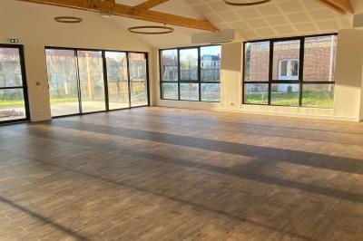 Des chèvres se tiennent près d'une clôture dans un champ herbeux entouré de barrières en bois.