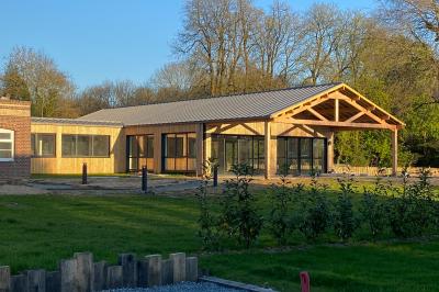 Des chèvres se tiennent près d'une clôture dans un champ herbeux entouré de barrières en bois.