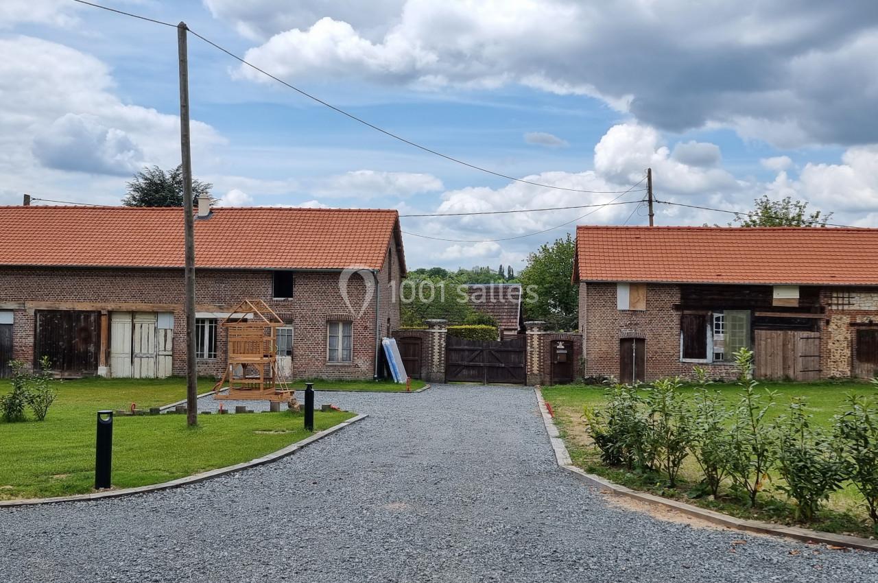 Deux bâtiments en briques avec toits en tuiles rouges, entourés de pelouses et d'une allée en gravier sous un ciel nuageux.