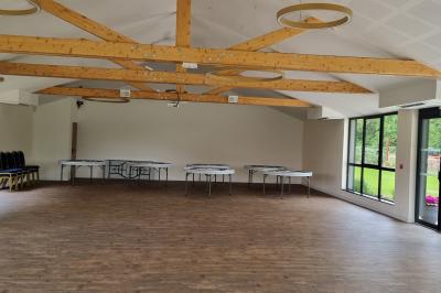 Des chèvres se tiennent près d'une clôture dans un champ herbeux entouré de barrières en bois.