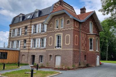 Des chèvres se tiennent près d'une clôture dans un champ herbeux entouré de barrières en bois.