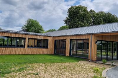 Des chèvres se tiennent près d'une clôture dans un champ herbeux entouré de barrières en bois.