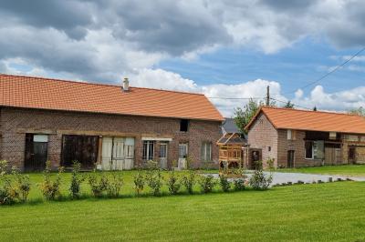 Des chèvres se tiennent près d'une clôture dans un champ herbeux entouré de barrières en bois.