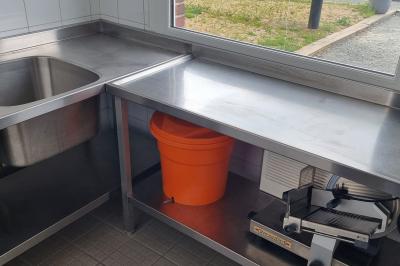 Des chèvres se tiennent près d'une clôture dans un champ herbeux entouré de barrières en bois.