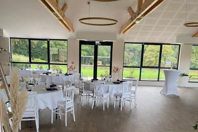 Des chèvres se tiennent près d'une clôture dans un champ herbeux entouré de barrières en bois.