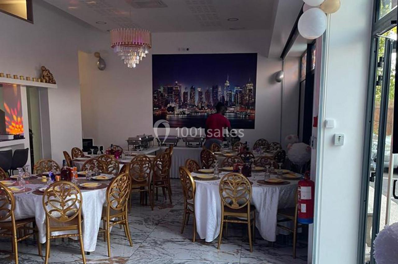 Salle de réception décorée avec des tables rondes dressées, un buffet en arrière-plan et un mur orné d'une photo de skyline.