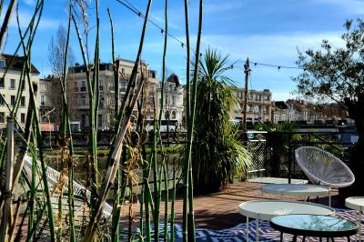 Décoration intérieure avec guirlandes lumineuses, sapin de Noël et vue sur des bâtiments à travers une verrière.