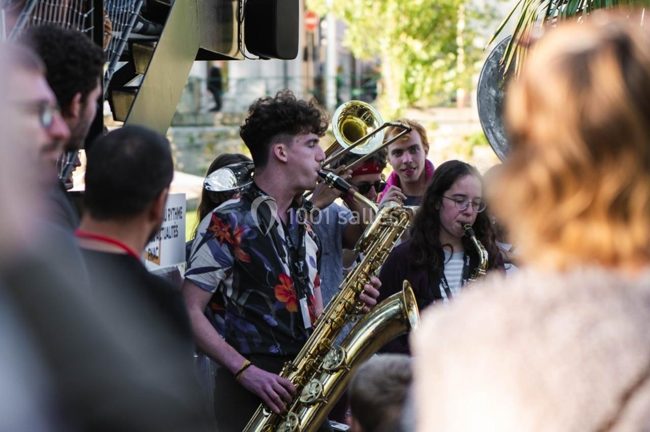 Un groupe de musiciens joue des instruments à vent en plein air devant un public.
