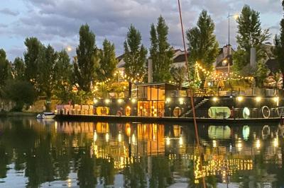 Décoration intérieure avec guirlandes lumineuses, sapin de Noël et vue sur des bâtiments à travers une verrière.