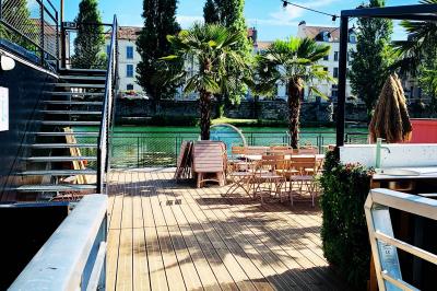 Groupe de personnes réunies dans un bar extérieur animé avec terrasse, palmiers et guirlandes lumineuses.