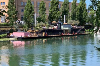 Groupe de personnes réunies dans un bar extérieur animé avec terrasse, palmiers et guirlandes lumineuses.