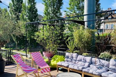 Groupe de personnes réunies dans un bar extérieur animé avec terrasse, palmiers et guirlandes lumineuses.