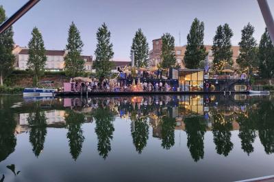 Groupe de personnes réunies dans un bar extérieur animé avec terrasse, palmiers et guirlandes lumineuses.