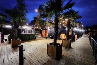 Groupe de personnes réunies dans un bar extérieur animé avec terrasse, palmiers et guirlandes lumineuses.