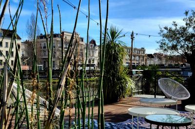 Groupe de personnes réunies dans un bar extérieur animé avec terrasse, palmiers et guirlandes lumineuses.