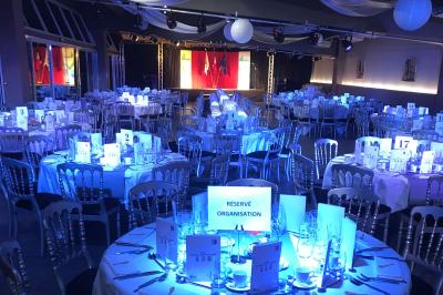 Allée pavée bordée d'arbres et de bâtiments en bois dans un cadre verdoyant sous un ciel dégagé.