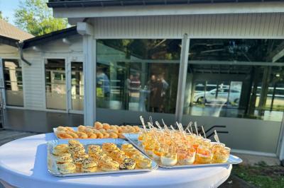Allée pavée bordée d'arbres et de bâtiments en bois dans un cadre verdoyant sous un ciel dégagé.