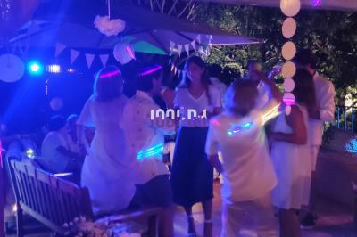 Des artistes en costumes brillants dansent sur une scène illuminée par des projecteurs colorés et un écran lumineux.